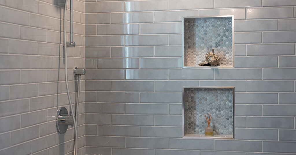 Modern shower with glossy subway tiles, built-in niches featuring small mosaic tiles, and a sleek chrome shower fixture, showcasing Best Tile For Shower Walls
