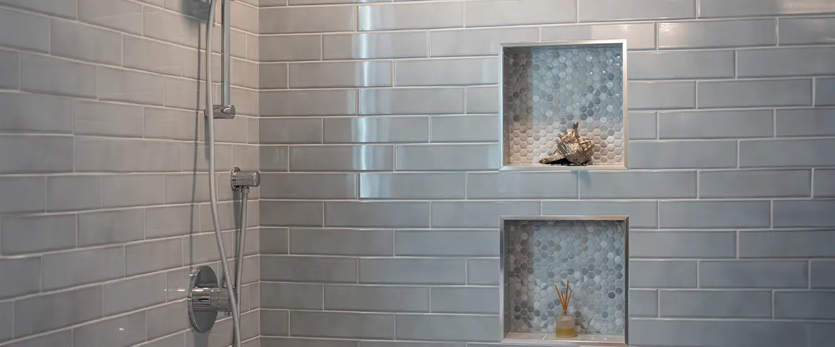 Modern shower with glossy subway tiles, built-in niches featuring small mosaic tiles, and a sleek chrome shower fixture, showcasing Best Tile For Shower Walls