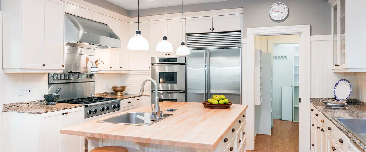 Classic white kitchen with butcher block island and stainless steel appliances