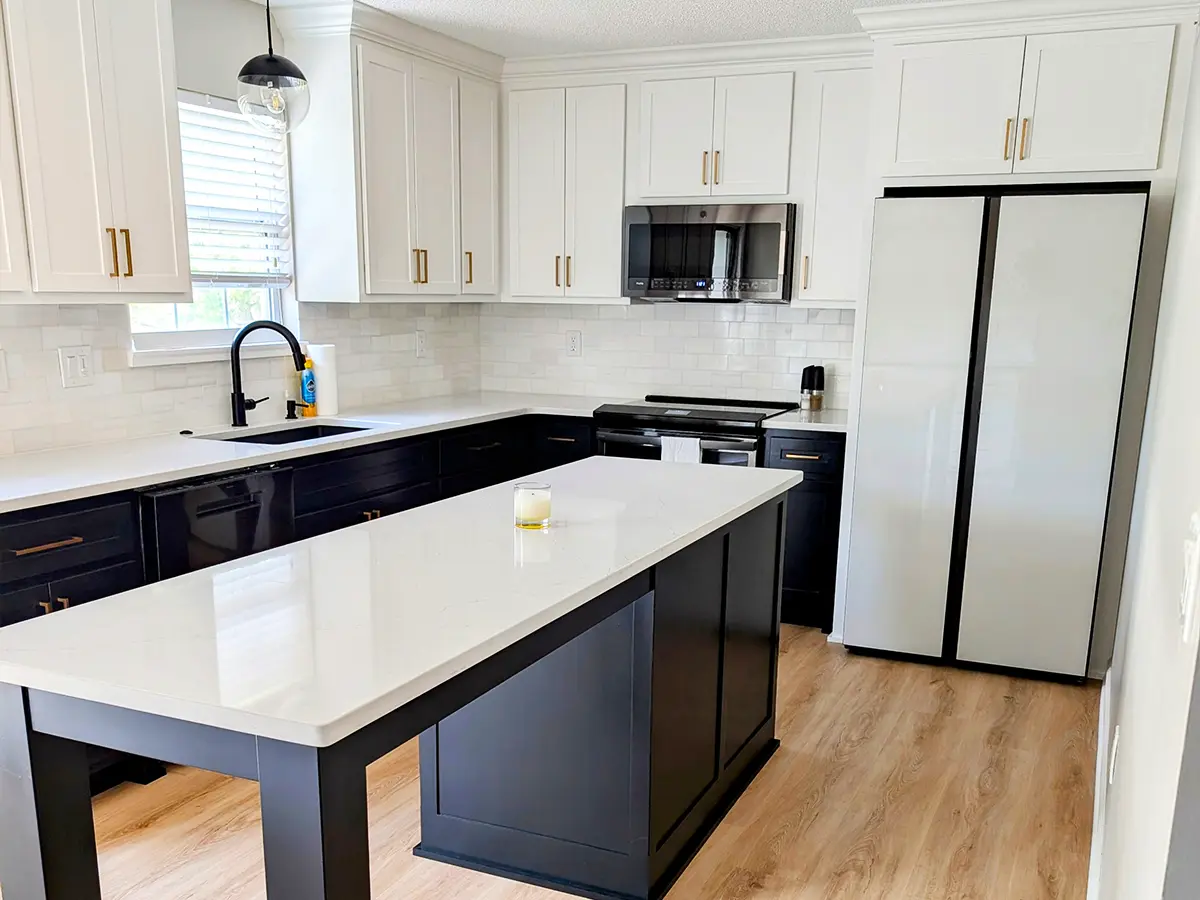 Modern kitchen with black cabinets, white countertops, and gold hardware, showcasing a stylish kitchen renovation.