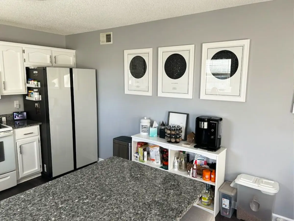 Before kitchen renovation with gray granite countertops and minimal storage, featuring white cabinets and appliances.