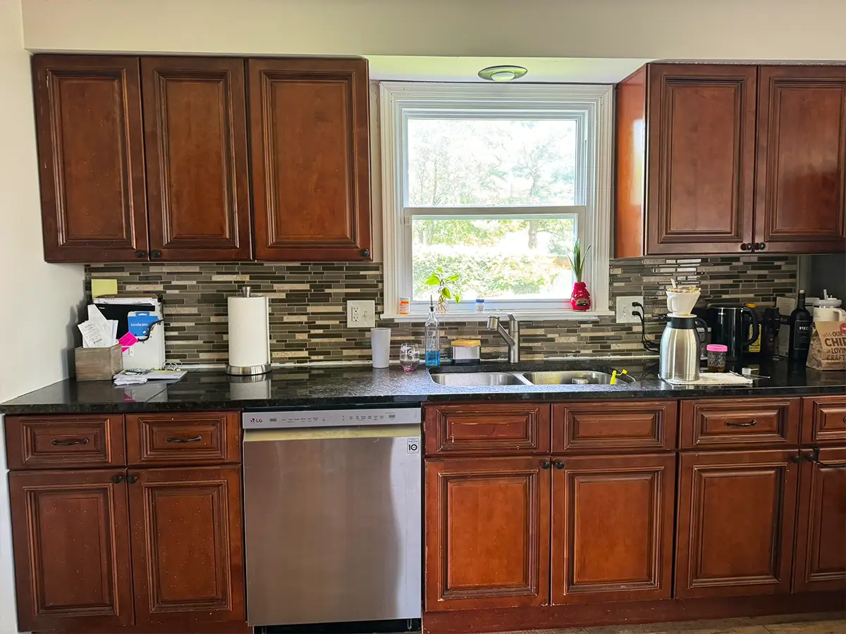 Traditional kitchen with dark wood cabinets and mosaic tile backsplash before remodeling.