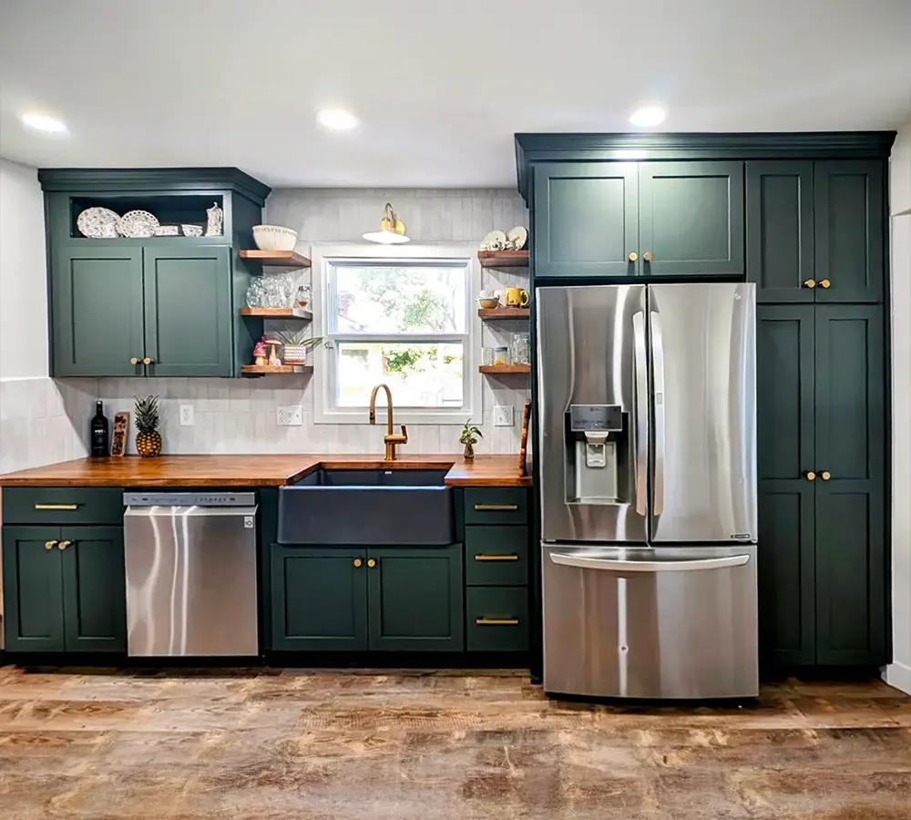 Modern kitchen with dark green cabinets, stainless steel appliances, butcher block countertops, and farmhouse sink.