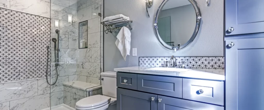 Elegant bathroom with a blue vanity, marble shower, and decorative tile
