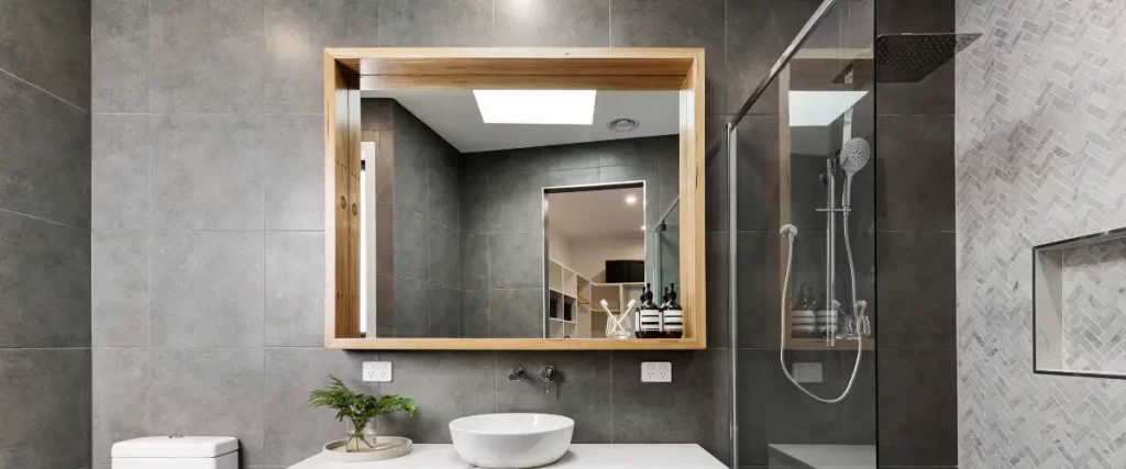 Modern bathroom with a large wooden-framed mirror and sleek fixtures