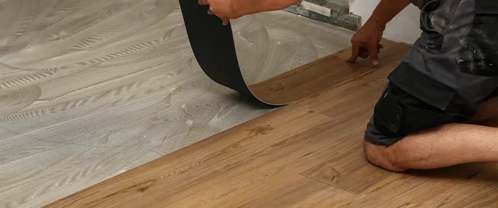 Professional installer laying luxury vinyl plank flooring over adhesive, showcasing modern home renovation and flooring upgrades.