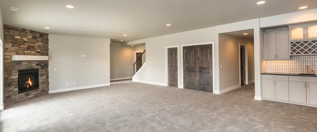 Spacious finished basement with a fireplace, carpet flooring, and a built-in wet bar, perfect for home improvement projects.